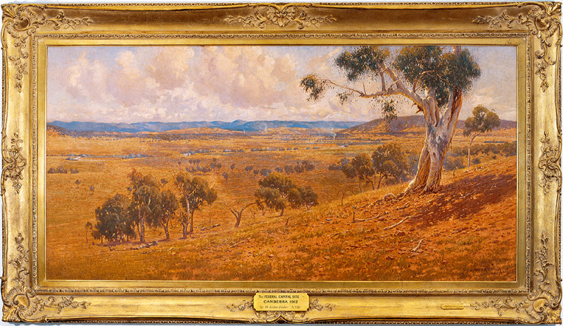 A painting of a dry hilly landscape with few trees. The painting is mounted within an ornate gold frame.