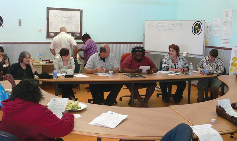 Senate committee hearing in the Kimberley, Western Australia. People are sitting at a table, listening to a witness talking.