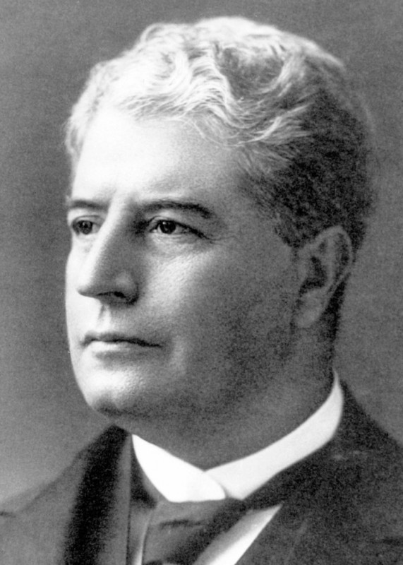 Black and white portrait of middle aged man with grey curly hair. 