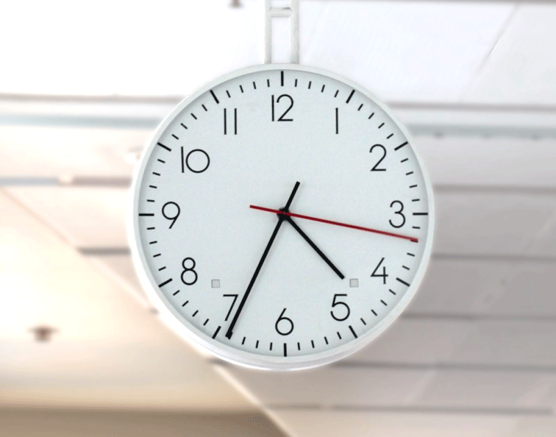 A clock at Australian Parliament House with a small red light and a small green light flashing.