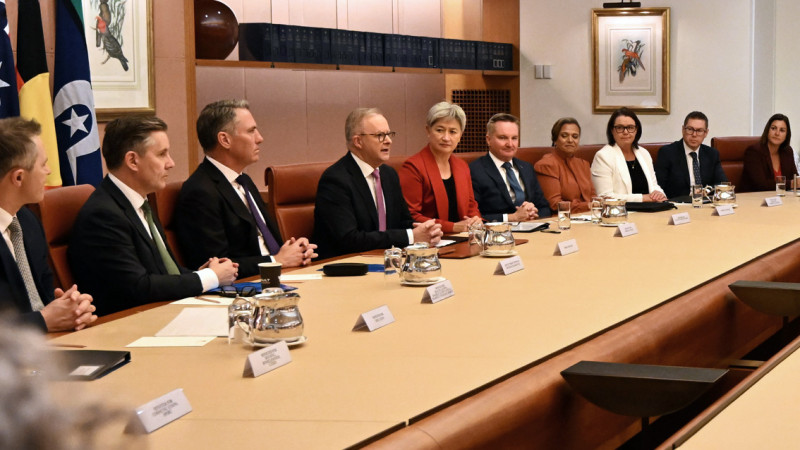 The Prime Minister and ministers having a meeting. They sit around a wooden table in the Cabinet Room.