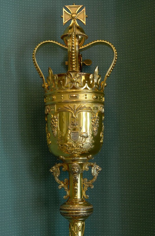 Details on the Mace clearly showing the crown and Australian Coat-of-Arms. The Mace is standing upright. 